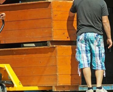 Zwei Helfer tragen einen Holzschrank aus einem Lkw – Möbelaufzug